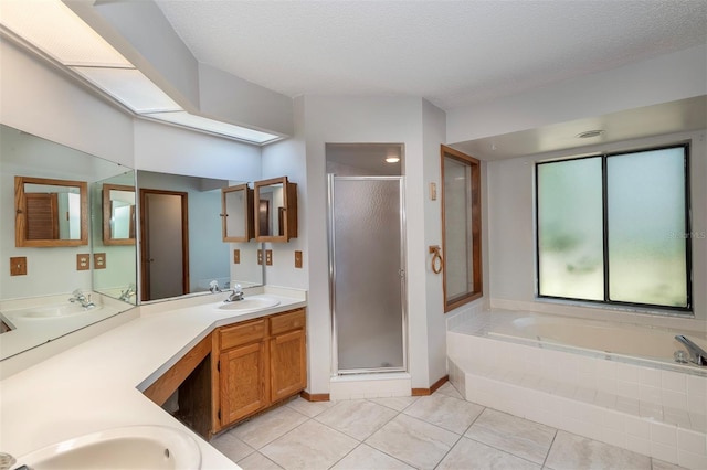 full bath featuring a stall shower, tile patterned flooring, a garden tub, double vanity, and a textured ceiling