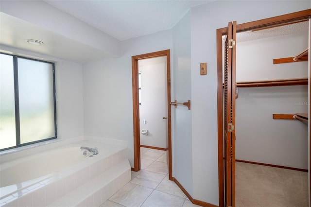 bathroom with a bath, a textured ceiling, and tile patterned flooring