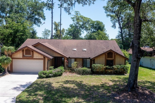 view of front of house with an attached garage, concrete driveway, a front lawn, and a shingled roof