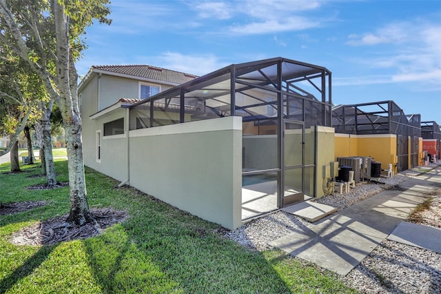 8919 Bismarck Palm Rd, Kissimmee, FL 34747 - view of property exterior featuring stucco siding, glass enclosure, cooling unit, and a yard