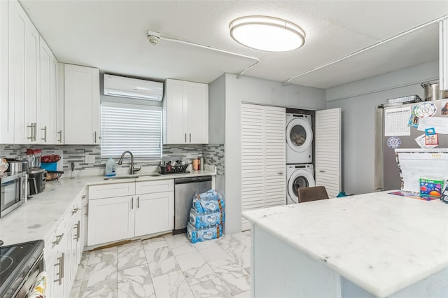 kitchen featuring a sink, a wall mounted AC, stacked washer / drying machine, light marble finish flooring, and appliances with stainless steel finishes