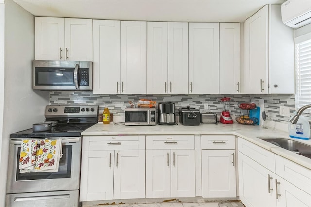 kitchen featuring appliances with stainless steel finishes, a sink, a wall mounted air conditioner, and tasteful backsplash