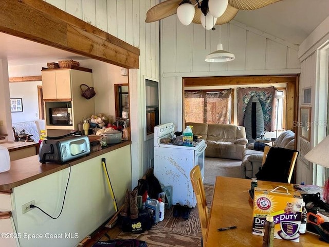 505 Lakeview Ave, Titusville, FL 32796 - kitchen with dark countertops, healthy amount of natural light, a ceiling fan, wooden walls, and high vaulted ceiling