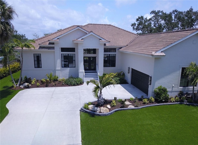 view of front of home with a tiled roof, a garage, stucco siding, and driveway