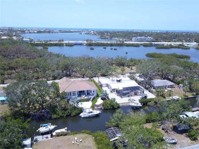 drone / aerial view of a nearby body of water and a tree filled landscape