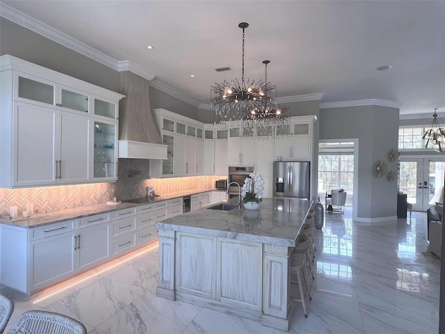 kitchen featuring stainless steel appliances, a chandelier, a sink, light marble finish floors, and crown molding