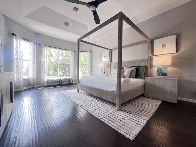 bedroom featuring baseboards, hardwood / wood-style floors, a tray ceiling, and ceiling fan