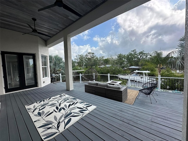 wooden deck featuring a ceiling fan, an outdoor living space, and french doors