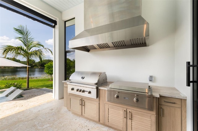 view of patio / terrace featuring area for grilling, exterior kitchen, and a water view