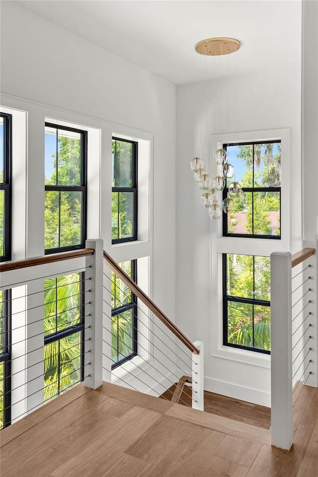 stairs with a chandelier, wood finished floors, and baseboards