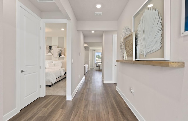 hallway featuring wood finished floors, baseboards, and recessed lighting