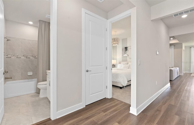 hallway featuring baseboards, wood finished floors, recessed lighting, and a chandelier