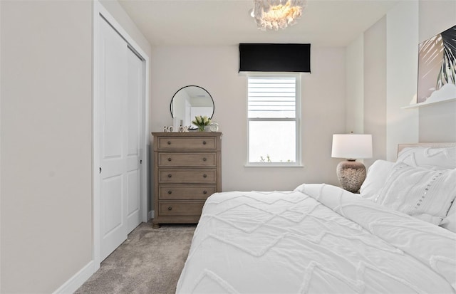 bedroom with light colored carpet, a closet, and a chandelier