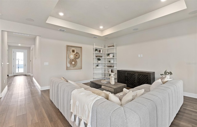 living room featuring baseboards, a tray ceiling, dark wood-style flooring, and recessed lighting
