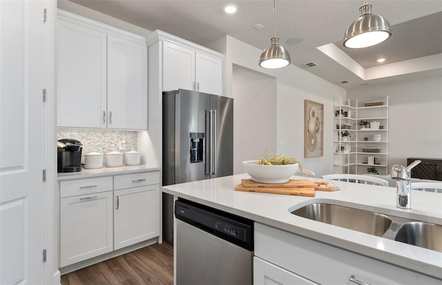 kitchen featuring stainless steel appliances, a sink, white cabinetry, dark wood-style floors, and pendant lighting