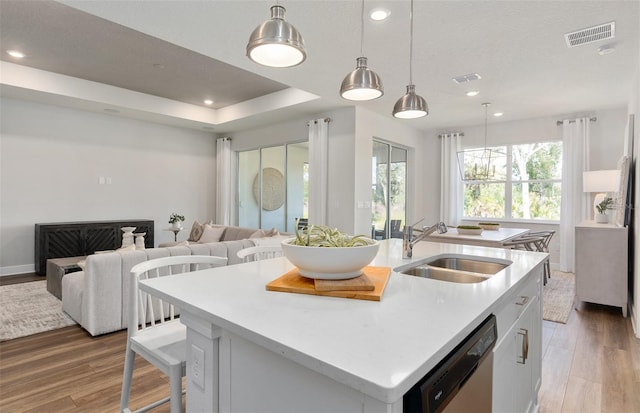 kitchen with a sink, stainless steel dishwasher, light wood-style flooring, open floor plan, and recessed lighting