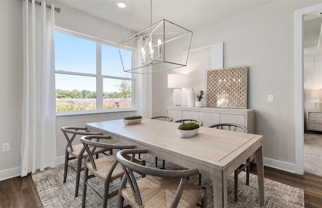 dining space featuring dark wood finished floors, baseboards, and a chandelier