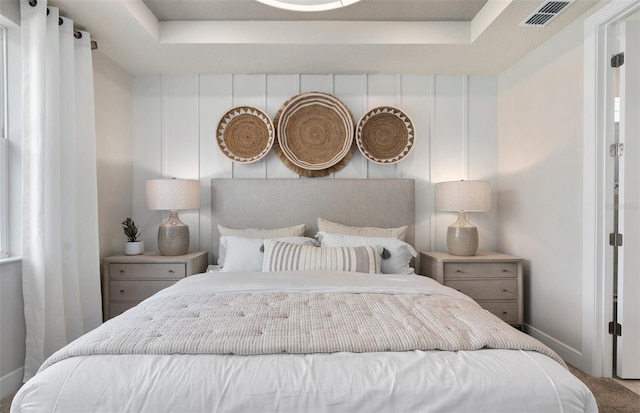 carpeted bedroom with baseboards and a raised ceiling
