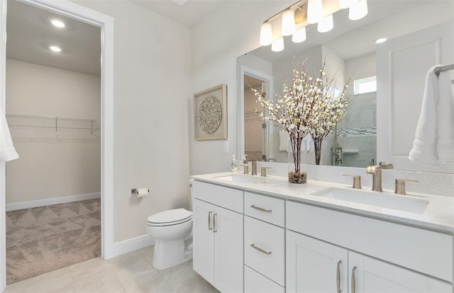 bathroom featuring a stall shower, a spacious closet, toilet, double vanity, and baseboards