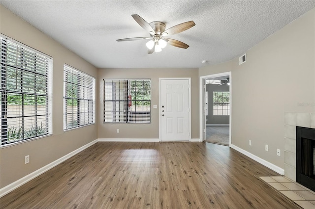 485 Forestway Cir Unit 108, Altamonte Springs, FL 32701 - unfurnished living room featuring a ceiling fan, a fireplace, wood finished floors, baseboards, and a textured ceiling