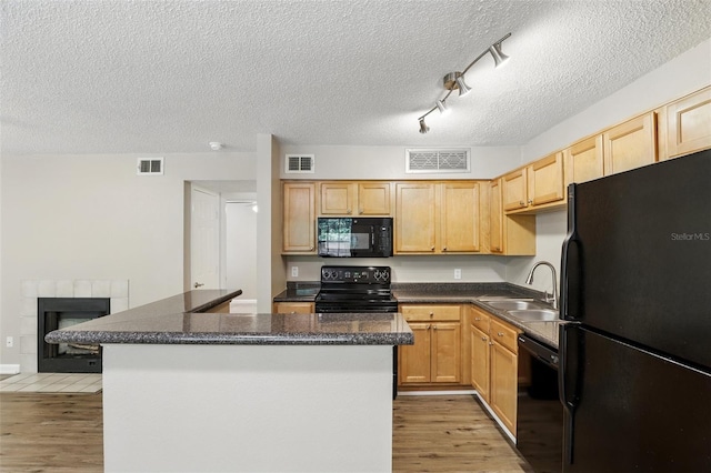 485 Forestway Cir Unit 108, Altamonte Springs, FL 32701 - kitchen with black appliances, a sink, light wood-style flooring, a textured ceiling, and dark countertops