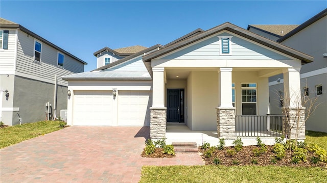 view of front facade featuring covered porch, an attached garage, decorative driveway, and stucco siding