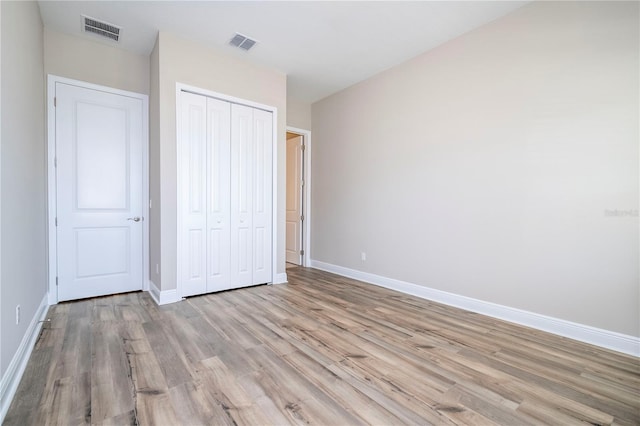 unfurnished bedroom with light wood finished floors, baseboards, and a closet