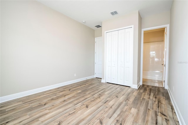 unfurnished bedroom with light wood-type flooring, a closet, and baseboards