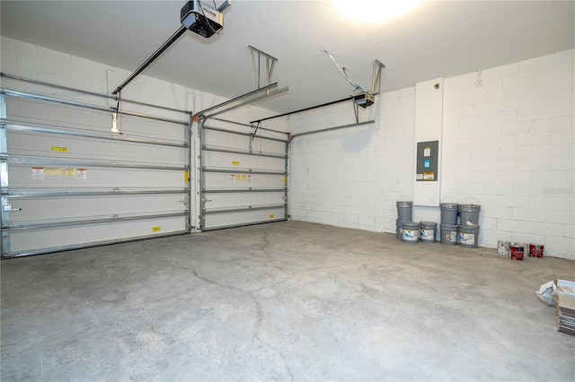 garage with a garage door opener, electric panel, and concrete block wall