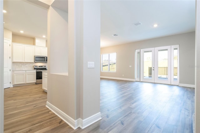 hall featuring light wood-style floors, baseboards, recessed lighting, and french doors