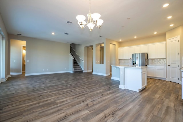 kitchen with stainless steel refrigerator with ice dispenser, recessed lighting, open floor plan, a chandelier, and white cabinets