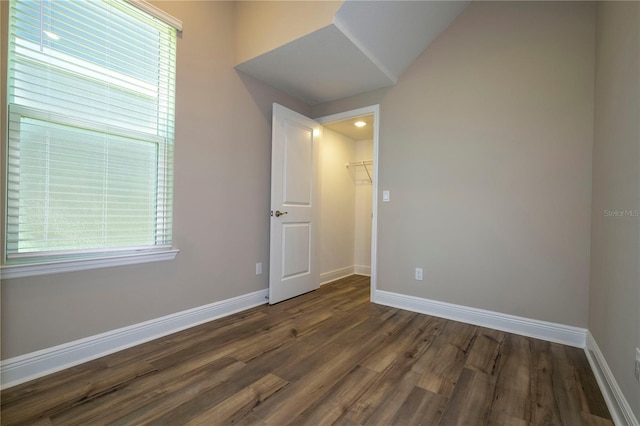 spare room featuring dark wood-style flooring and baseboards