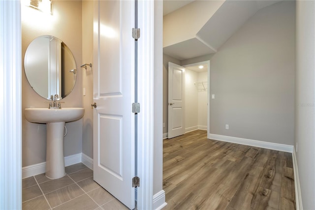 bathroom featuring baseboards, wood finished floors, and a sink