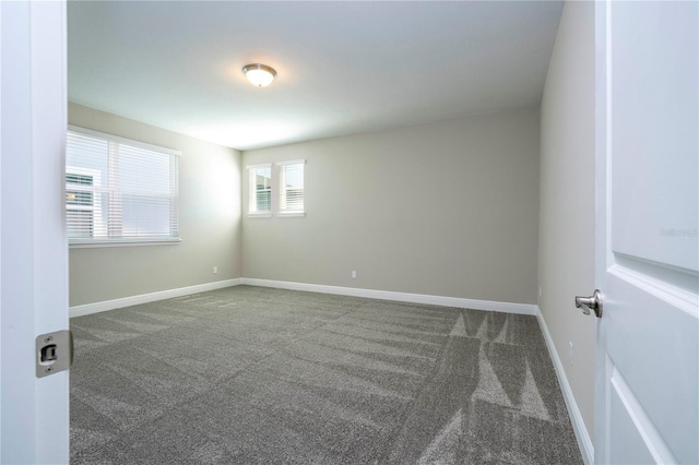 carpeted empty room featuring baseboards