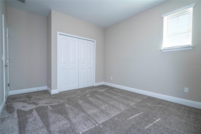 unfurnished bedroom with carpet floors, a closet, and baseboards