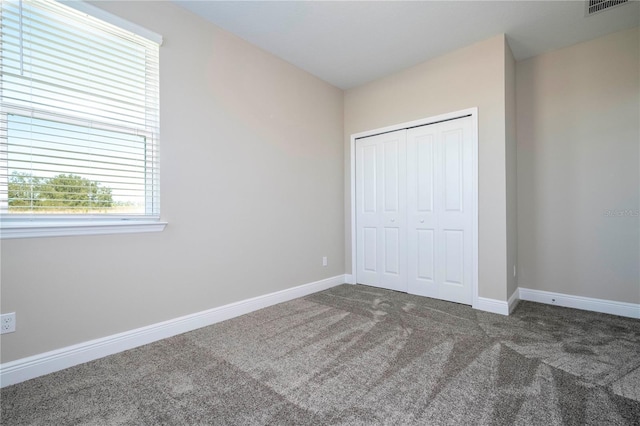 unfurnished bedroom with carpet floors, a closet, and baseboards