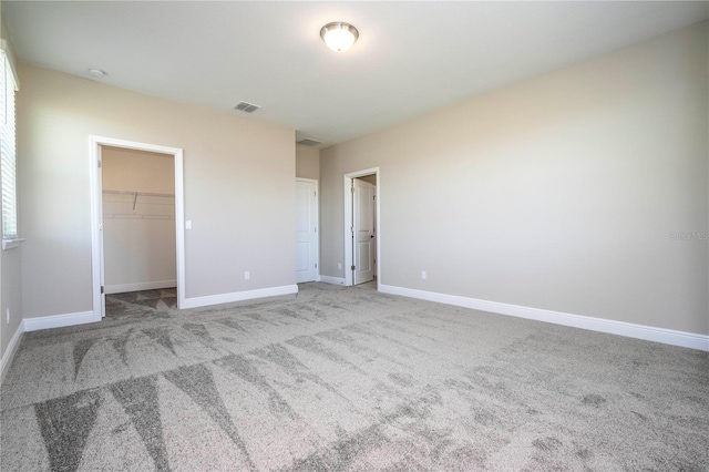 unfurnished bedroom featuring carpet flooring, baseboards, a spacious closet, and a closet