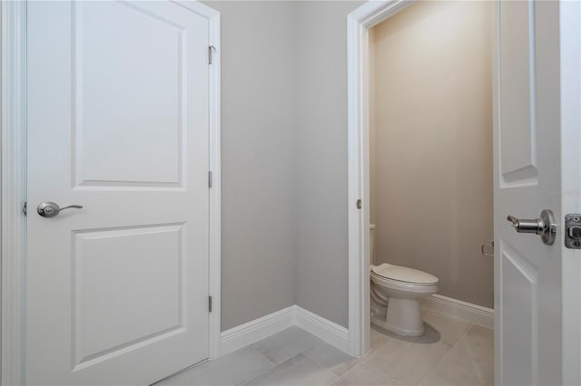 bathroom featuring baseboards, toilet, and tile patterned flooring