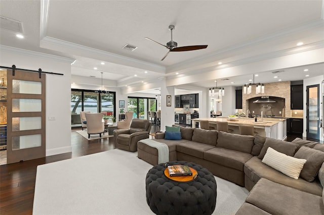 1455 Kelso Blvd, Windermere, FL 34786 - living room with ornamental molding, a barn door, ceiling fan, dark wood-style floors, and a tray ceiling