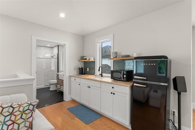 1455 Kelso Blvd, Windermere, FL 34786 - kitchen featuring black appliances, a sink, white cabinetry, light wood-style floors, and open shelves