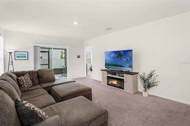 living area featuring carpet floors, baseboards, a glass covered fireplace, and recessed lighting
