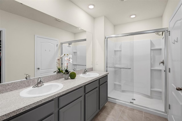 bathroom featuring a stall shower, double vanity, and tile patterned floors