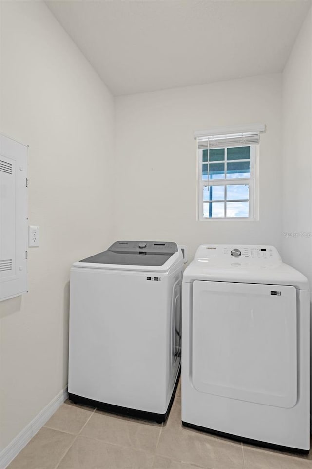 clothes washing area with separate washer and dryer, baseboards, and light tile patterned floors