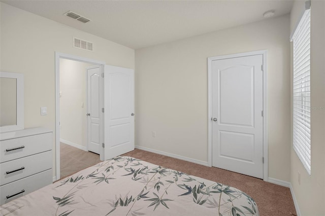 bedroom with multiple windows, light colored carpet, and baseboards