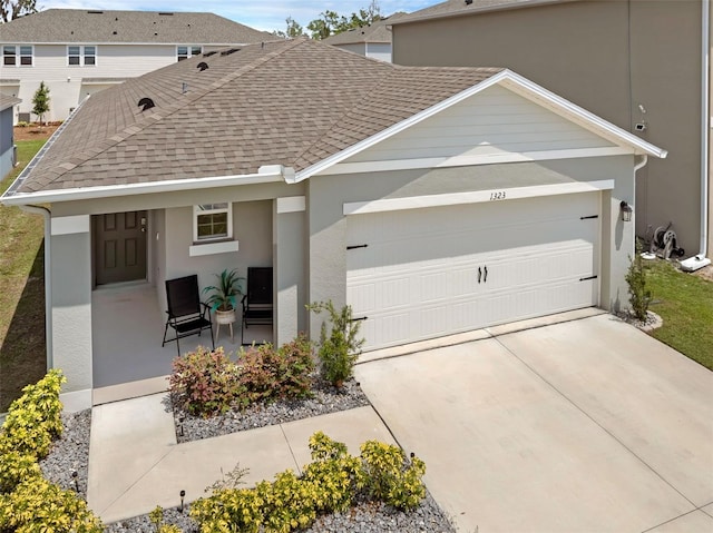 view of front facade with an attached garage, driveway, stucco siding, and roof with shingles