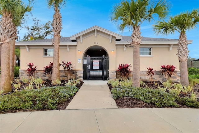 entrance to property featuring stucco siding, stone siding, and a gate