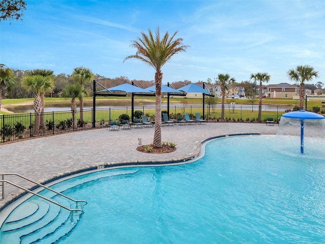 community pool with fence, a patio area, a water view, and a residential view