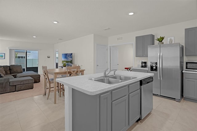 kitchen with appliances with stainless steel finishes, gray cabinets, a sink, light countertops, and light tile patterned floors