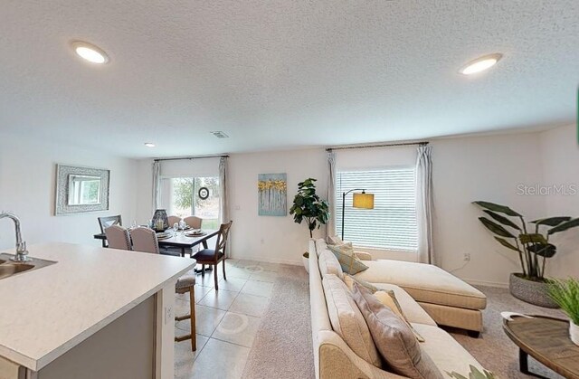 living room with recessed lighting, a textured ceiling, and light tile patterned floors