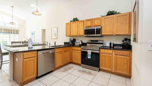 2805 Lido Key Ct, Kissimmee, FL 34747 - kitchen with appliances with stainless steel finishes, a sink, a peninsula, light tile patterned floors, and dark countertops